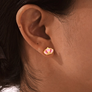 Close-up of pink crown earring worn on ear showing gold finish and enamel detail