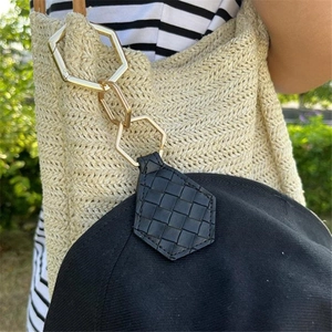 Detail of leaf-shaped PU leather hat clip with golden hexagon ring attached to bag