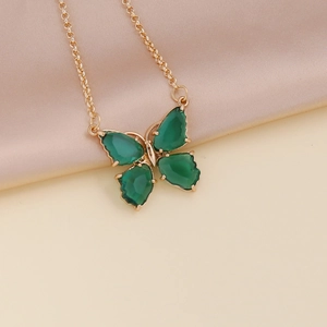 Detail of green butterfly pendant with gold plating on soft beige satin fabric