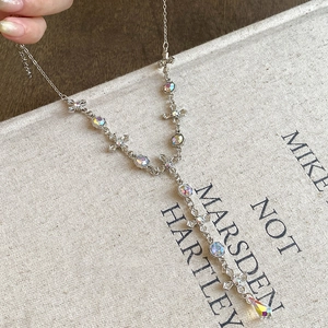 Macro view of silver Y-shaped necklace with cross links and iridescent crystal charms