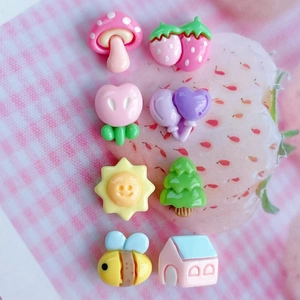 Close-up of assorted glossy mini resin charms including mushroom, bee and flower shapes