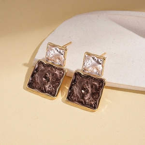 Close-up of geometric square earrings with hammered texture and vintage gold edges