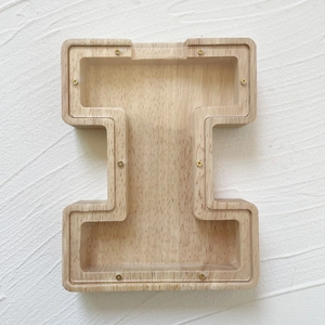 Macro shot of an I-shaped wooden letter piggy bank with a clear acrylic front panel