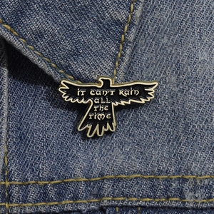 Creative eagle wings enamel brooch with 'IT CAN'T RAIN ALL THE TIME' text on denim jacket
