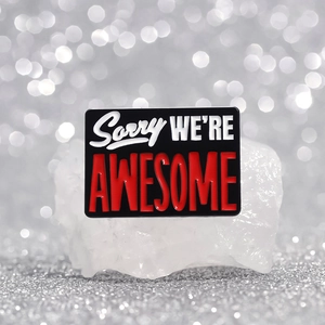 Rectangular enamel pin with Sorry WE'RE AWESOME lettering on premium mineral stone
