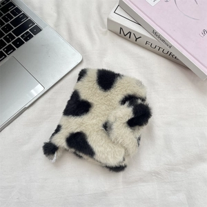 Detail of plush cow print storage bag on a modern desk with magazines and laptop