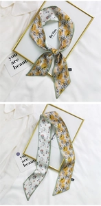 Close-up of narrow silk scarf featuring abstract face prints and soft green piping detail