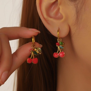 Detailed view of red cherry enamel earrings with gold-plated hooks and beaded leaf accents