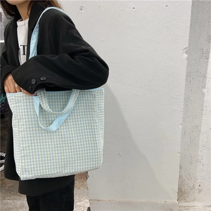 Detalle de bolso de lona con cuadros azules y amarillos llevado al hombro en el exterior