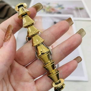 Primo piano di un bracciale in metallo dorato con maglie coniche indossato al polso