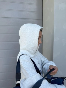 Λεπτομέρεια γκρι oversized φούτερ με τύπωμα L'AVENIR και πλαϊνό προφίλ σε μοντέλο