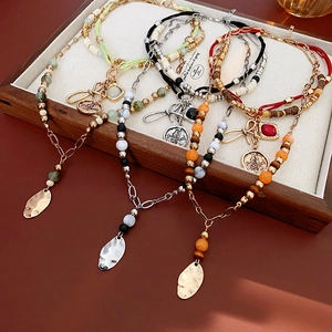 Bohemian multi-layer beaded necklace with metal leaf charms and natural stones on a tray