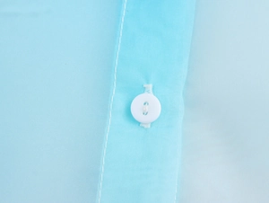 Dettaglio del tessuto in organza azzurro con bottone bianco e cuciture di alta qualità