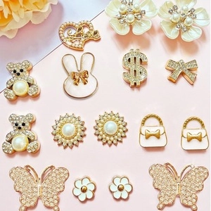 Detailed view of DIY pearl charms including rhinestone heart and bear motifs