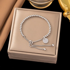Detail of silver beaded bracelet featuring a round polished charm and adjustable slide clasp