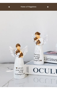 Detalle de figura de ángel de resina con perro y texto conmemorativo en el vestido