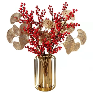 Detailed view of red artificial berries and golden ginkgo leaves in a glass vase