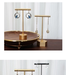 Detailed shot of celestial cat earrings and gold drop earrings on metal jewelry stand