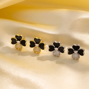 Detailed view of four-leaf clover stud earrings with black enamel and pavé crystals