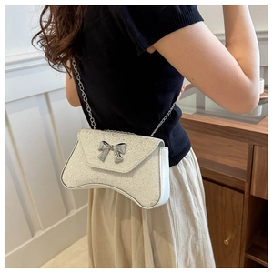 Close-up of silver sequin crescent bag with metallic bow detail and chain strap