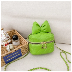 Green quilted mini bag with bow decoration and golden chain strap in a lifestyle setting