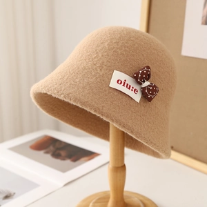 Cute khaki lamb wool bucket hat for women with a brown polka dot bow and oiu:e label