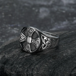 Vintage silver Viking cross ring with Celtic knot reliefs on a dark stone surface