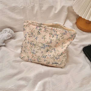 Close-up of floral canvas makeup bag with blue and red patterns on white fabric