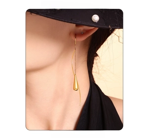 Close-up of model wearing gold teardrop tassel earrings with flowing metal lines