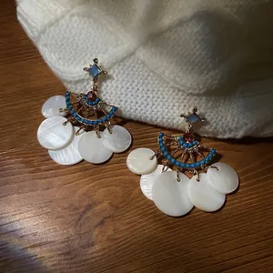 Detail of fan-shaped shell tassel earrings with blue turquoise beads and gold finish