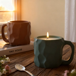 Close-up of matte textured candle cups with irregular geometric facets in a warm sunset