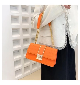 Detail van oranje tas met krokodillenmotief, gouden ketting en metalen slot sluiting