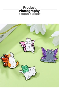 Détail de broches chat en émail avec ailes de papillon colorées sur fond vert clair doux