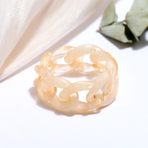 Macro view of jelly-colored resin chain ring featuring marble texture on white silk background