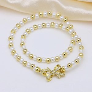 Detailed close-up of natural pearl necklace with gold beads and sparkling bow pendant