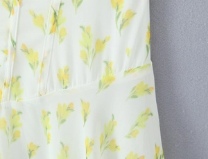 Dettaglio del motivo floreale giallo su abito in chiffon bianco con cuciture