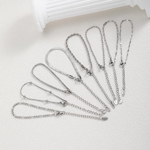 Macro detail of eight minimalist stainless steel silver chain bracelets with lobster clasps
