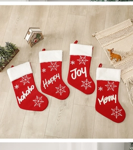 Detail of four red knitted Christmas stockings with snowflake patterns on wood floor