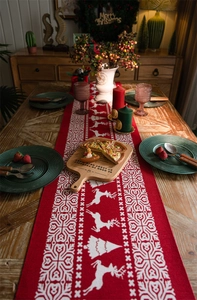 Detailed view of red Christmas table runner with white reindeer and snowflake motifs