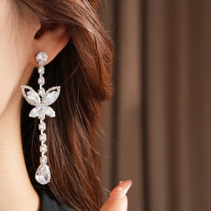 Close-up of silver butterfly drop earrings with sparkling pear-shaped zircon stones