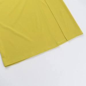 Detailed close-up of the yellow knit dress side slit and fine stitching on the hem