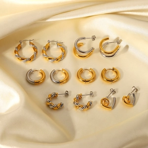 Collection of golden and silver twist hoop earrings on elegant yellow silk background