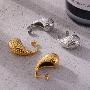 Boucles d'oreilles goutte rétro martelées en or et argent sur fond texturé chic