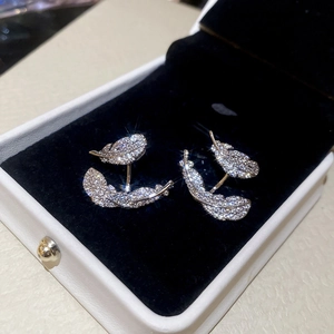 Macro detail of silver feather earrings with sparkling cubic zirconia on black velvet