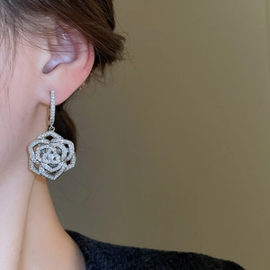 Macro detail of hollow rose dangle earrings with sparkling cubic zirconia on model