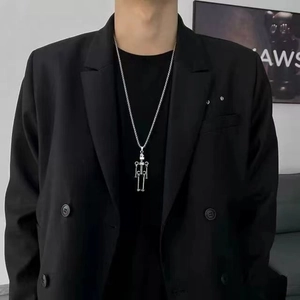 Detailed view of vintage silver skeleton robot pendant necklace worn by a model in black suit