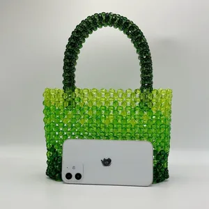 Detailed view of handmade beaded tote bag in green gradient with iPhone for scale