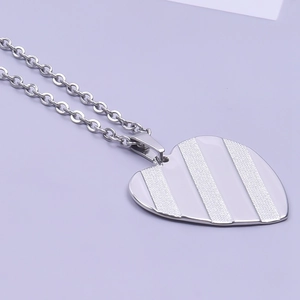 Close-up of a silver heart pendant featuring striped matte and polished finishes on a chain