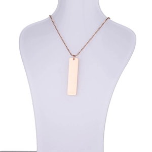 Detailed view of a rose gold rectangle pendant necklace on a white mannequin bust