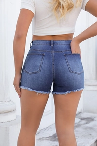 Detail of high-waisted distressed denim shorts with frayed hems and light blue wash